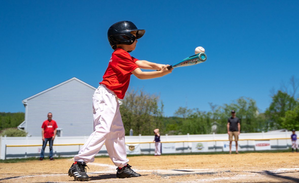 青空の下でバッティングをする子どもと屋外スポーツの熱中症対策のイメージ